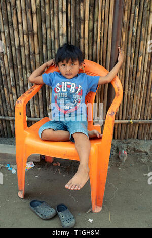 Native kuna boy sitting on plastic chair in Carti island 