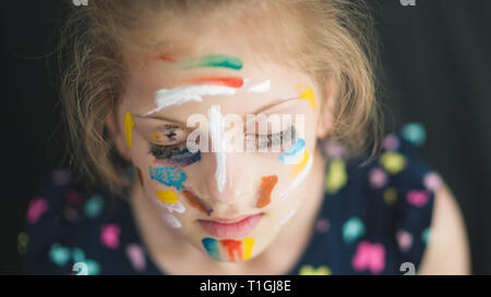beautiful little girl in multicolored with eyes closed with painted colorful face dreaming Stock Photo