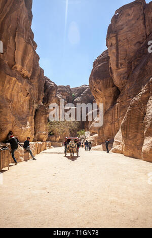 PETRA, JORDAN - MARCH 15, 2019: Tourists take a scenic ride inside the canyons of Petra with a horse-drawn wagon. Stock Photo