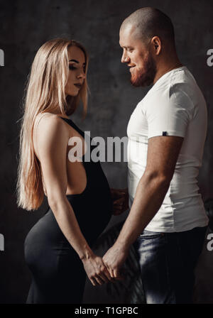 Pregnant woman stands in black dress with her husband. Stock Photo