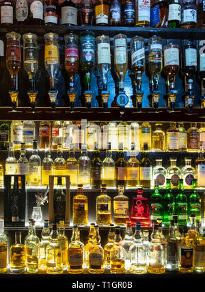 A large selection of Scottish Whiskies illuminated on glass shelves and in optics, Scotland