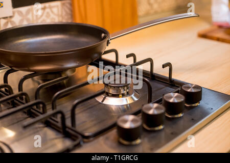 The new frying pan on Brand new gas stove panels.Classic four burner gas stove with brass knobs. Selective focus.Burners on a silver gas stove in the Stock Photo
