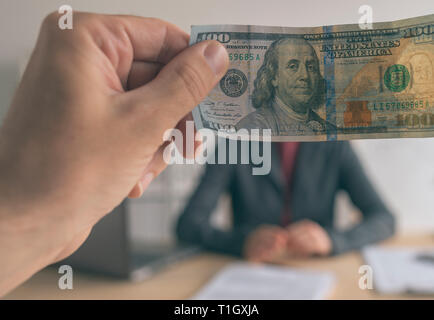 Business bribe money and corruption, man offering cash US dollar paper currency to female business person Stock Photo