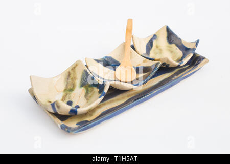 three wells of ceramic stoneware and wooden spoons with white background Stock Photo