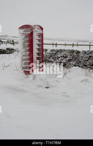 red telephone box covered in snow in rural location Stock Photo