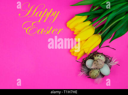 Easter background. Easter eggs, yellow tulips and festive inscription Happy Easter. copy space Stock Photo