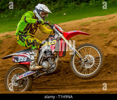 British motocross championship racing at Cadders Hill, Lyng, Norfolk. Honda rider pulls a wheelie while accelerating hard up a hill. Stock Photo