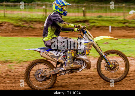 British motocross championship racing at Cadders Hill, Lyng, Norfolk. Suzuki rider pulling an un-intentional wheelie accelerating hard to catch the le Stock Photo