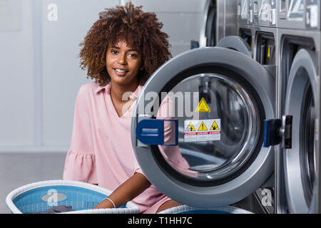 Young black African American woman washing her clothes in a automatic laundry Stock Photo