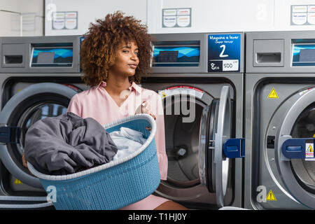 Young black African American woman washing her clothes in a automatic laundry Stock Photo