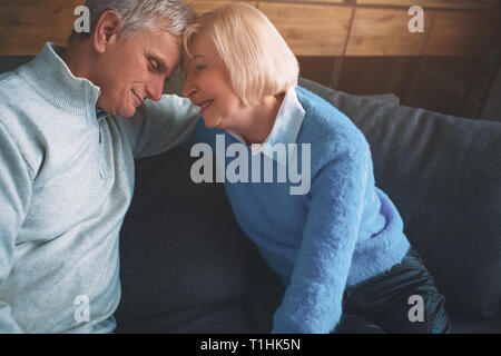 Close up of lovely old couple sitting together on the couch. The Stock Photo