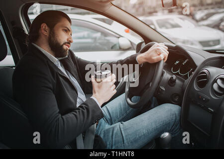 The driver going on the road, speaking on the phone, working with documents at the same time. Businessman doing multiple tasks. Multitasking business Stock Photo