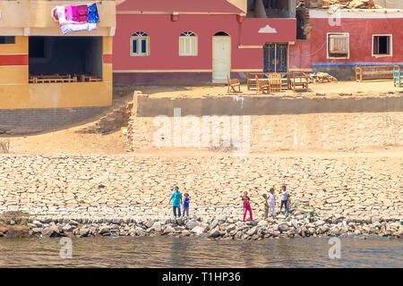 Aswan, Egypt - September 13, 2018: Children waving to Nile Cruise tourists next to the Nile River, southern Egypt Stock Photo