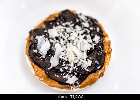 Flat top closeup of rice cake with chocolate drizzle sauce syrup vegan vegetarian snack dessert one single piece on white plate isolated and peanut bu Stock Photo