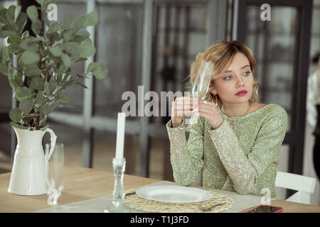 Young wife sitting alone at the table with candles and glasses Stock Photo