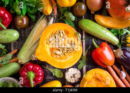 Fresh vegetables scaterred on a rustic dark textured table. Autumn background Stock Photo