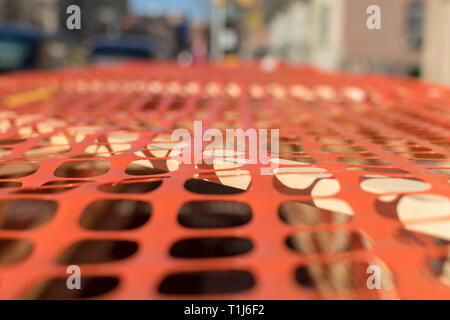 Construction site covered by a piece of perforated orange plastic, draped over a simple wooden frame made of 2x4s, Harlem, New York City, NY, USA Stock Photo