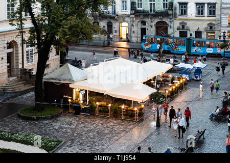 Lviv, Ukraine - July 31, 2018: Aerial high angle view of Ukrainian city in old town market with cafe restaurant, water fountain in evening illuminated Stock Photo