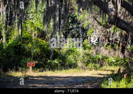 Sign to Deep hole sinkhole with dirt hiking trail and nobody, oak trees covered in Spanish moss canopy at Myakka River state park, Sarasota Florida Stock Photo