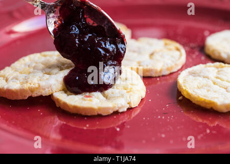Eating plum jam on a red plate with corn / rice biscuits Stock Photo