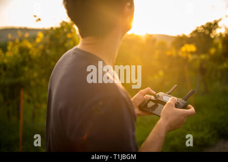 Young man flying a drone in warm evening sunlight Stock Photo