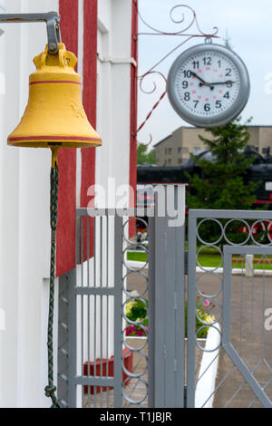 Parts of the old railway station. Retro clock and bell on the train platform. Stock Photo