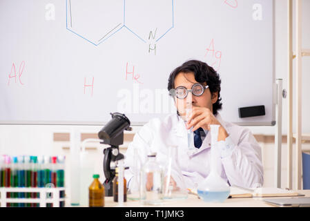 Young funny chemist in front of white board Stock Photo