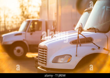 Middle duty rigs semi Trucks with box trailers standing at the gates of the warehouse for loading commercial cargo for the next local deliveries flood Stock Photo