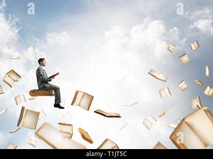 Man reading book and many of them flying in air Stock Photo