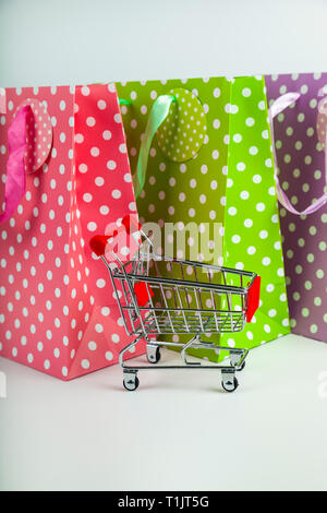 Three multi-colored shopping bags  and shopping cart. Stock Photo