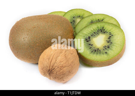 Whole and sliced kiwi fruit next to the walnuts isolated on a white background Stock Photo
