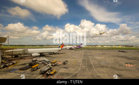 The busy scene at Kuala Lumpur  International Airport with am airplane taking off as others are refueled and deliver or pick-up passengers Stock Photo