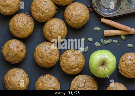 Muffins on black background with apple, cinnamon and pumpkin seeds - Overhead photo Stock Photo