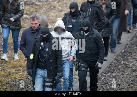 Wiesbaden, Germany. 27th Mar, 2019. Accompanied by masked police officers, Ali B., accused of murdering 14-year-old Susanna, is led along a railway line near Erbenheim. To his left is his lawyer. Here the man, who came from Iraq, allegedly raped the girl, then killed her and buried her body. Credit: Boris Roessler/dpa/Alamy Live News Stock Photo