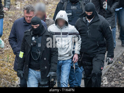 Wiesbaden, Germany. 27th Mar, 2019. Accompanied by two masked police officers, Ali B., accused of murdering 14-year-old Susanna, is led along a railway line near Erbenheim. To his left is his lawyer. Here the man, who came from Iraq, allegedly raped the girl, then killed her and buried her body. Credit: Boris Roessler/dpa/Alamy Live News Stock Photo