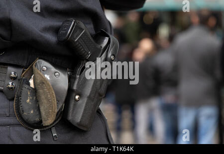 Bielefeld, Germany. 27th Mar, 2019. The weapon of a policeman standing before the district court. A trial against eight men on suspicion of a serious breach of the peace begins under great security precautions. The defendants, aged between 20 and 38, are to belong to an extended family. After an argument, one of the men was expelled from a discotheque. The 27-year-old is said to have called his brother and other relatives to it. The argument escalated. Credit: Friso Gentsch/dpa/Alamy Live News