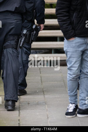 Bielefeld, Germany. 27th Mar, 2019. Policemen carry guns in front of the district court. A trial against eight men on suspicion of a serious breach of the peace begins under great security precautions. The defendants, aged between 20 and 38, are to belong to an extended family. After an argument, one of the men was expelled from a discotheque. The 27-year-old is said to have called his brother and other relatives to it. The argument escalated. Credit: Friso Gentsch/dpa/Alamy Live News