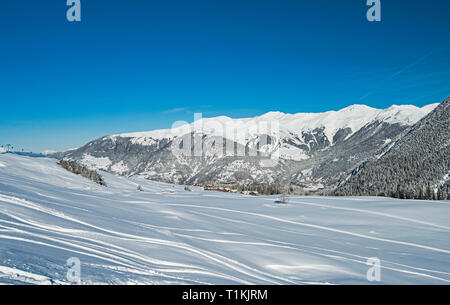 Fresh off piste ski slope in winter alpine mountain resort with powder snow tracks and mountains Stock Photo