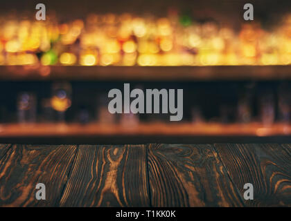 Empty wooden bar table top with defocused background. Bar counter table in front of blurred beaverages and drinks. Copy Space Stock Photo
