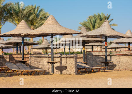 Wicker sun parasols and sun beds on the beach Stock Photo