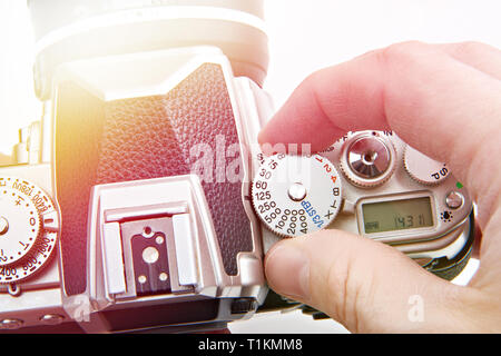 Photographer setting shutter control dial on retro SLR camera closeup Stock Photo