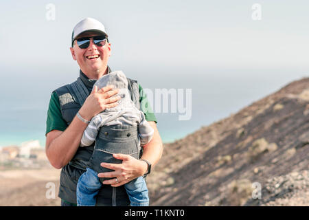 Father with his 9 months son in baby carrier on the trail in the mountains Stock Photo