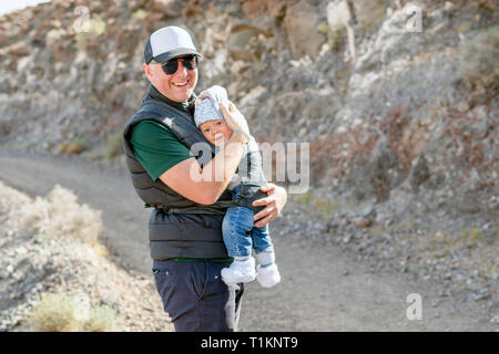 Father with his 9 months son in baby carrier on the trail in the mountains Stock Photo