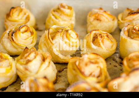 Fresh buns in the form of roses with apples are on the baking tray Stock Photo