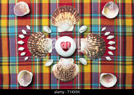 A symetrical pattern made with a collection of shells and white stone with red heart in the middle Stock Photo