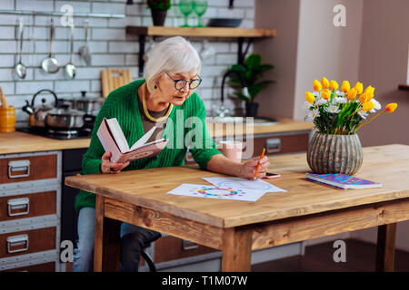 Attractive concerned dame in years doing vedic charts with pencil Stock Photo