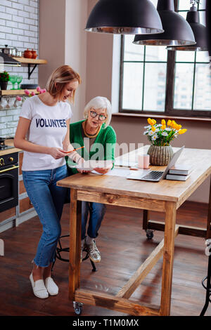 Pleasing social worker passing pencil to elderly woman for signing Stock Photo