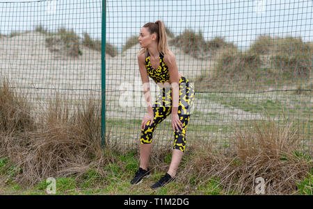 sporty woman resting with her hands on her kness catching her breath Stock Photo