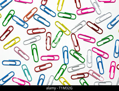 A lot of multi-colored stationery clips for documents lie on a white background. Close-up Stock Photo