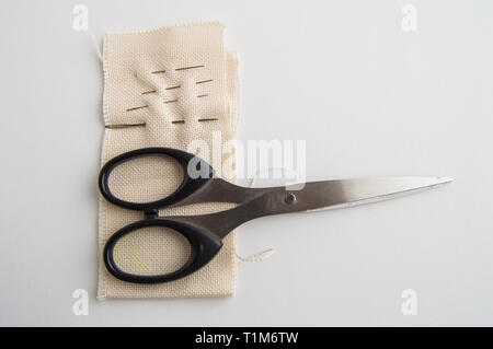 Sewing supplies SCISSORS, NEEDLE, fabric on white table, concept of minimalist, top, and accessories for handmade tailor.